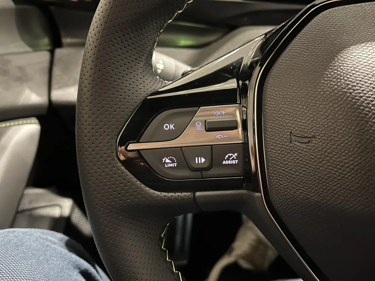 Gros plan sur le côté gauche du volant cuir perforé de la Peugeot 308 GT 2024 avec commandes de régulateur et limiteur.