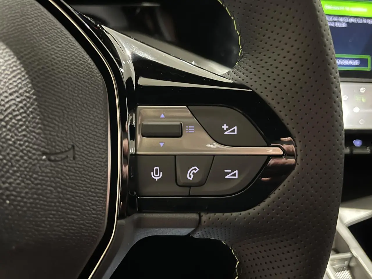 Gros plan sur les commandes du volant cuir perforé de la Peugeot 308 GT gris Selenium, avec éclairage des touches.