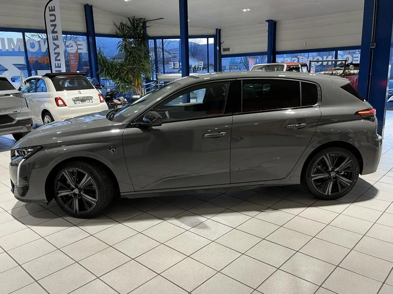 Profil côté gauche de la Peugeot 308 GT gris sélénium avec jantes alliage 18'' Kamakura en showroom.