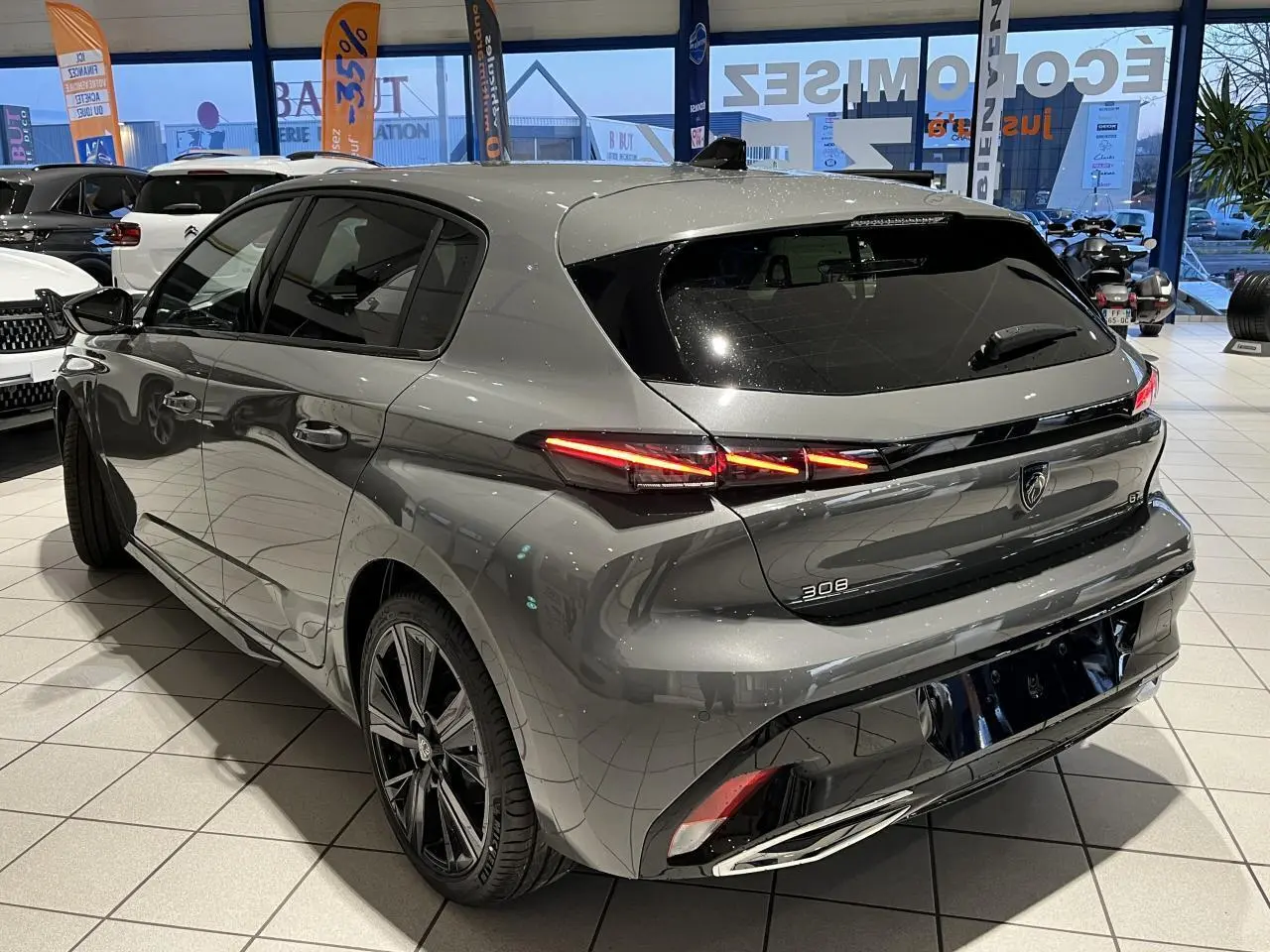 Vue 3/4 arrière droit d'une Peugeot 308 gris sélénium avec feux arrière LED griffés et jantes alliage 18 pouces.