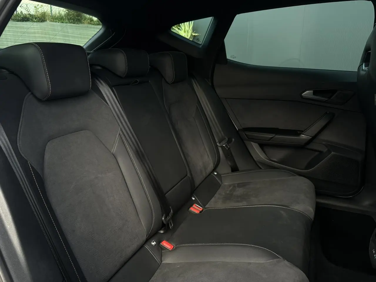 Vue latérale intérieure des sièges arrière en suédine noir Asphalte du CUPRA Formentor 2025 avec ceinture de sécurité visible.