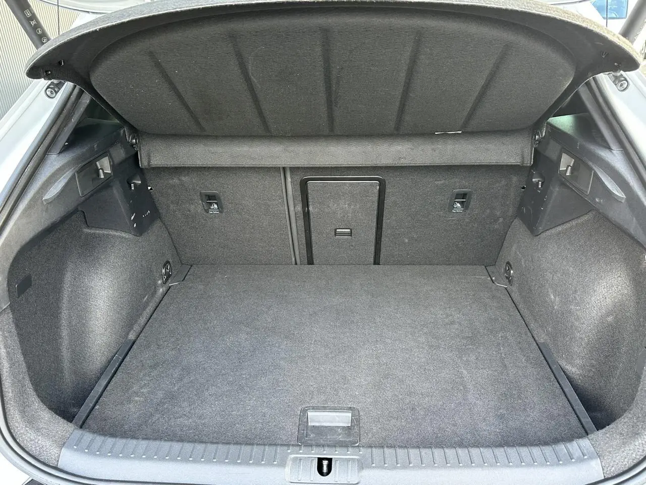 Coffre ouvert vu de l'arrière du CUPRA Formentor blanc Neige, intérieur de coffre en tissu gris.