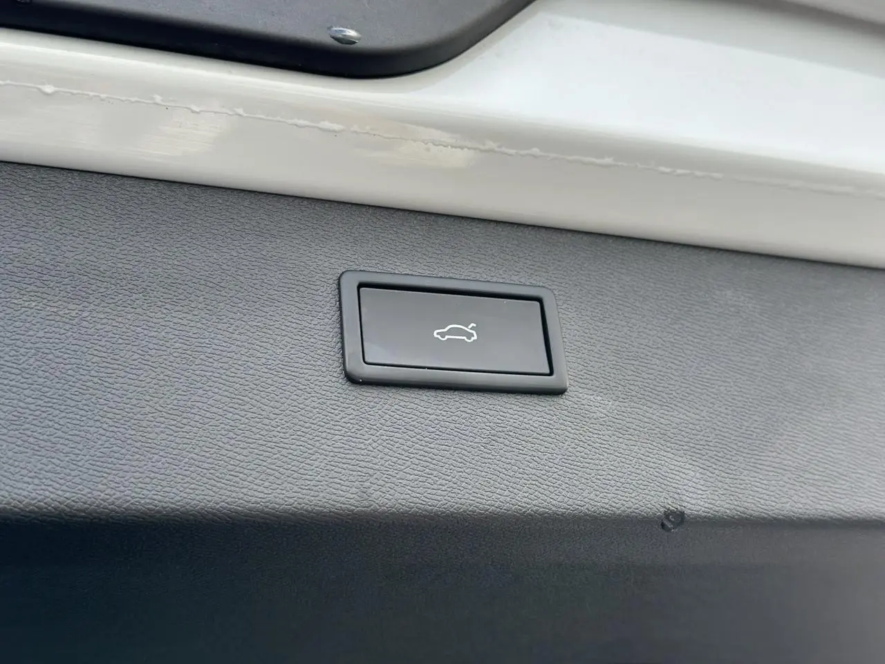 Gros plan sur le bouton d'ouverture électrique du hayon, intégré dans le coffre blanc neige du CUPRA Formentor 2025.