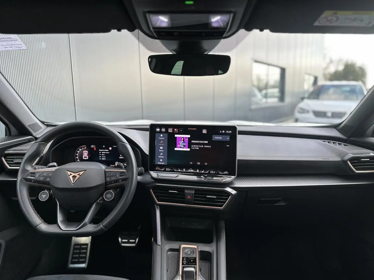 Vue frontale de l'intérieur du CUPRA Formentor blanc Neige 2025, avec tableau de bord numérique et écran tactile central.