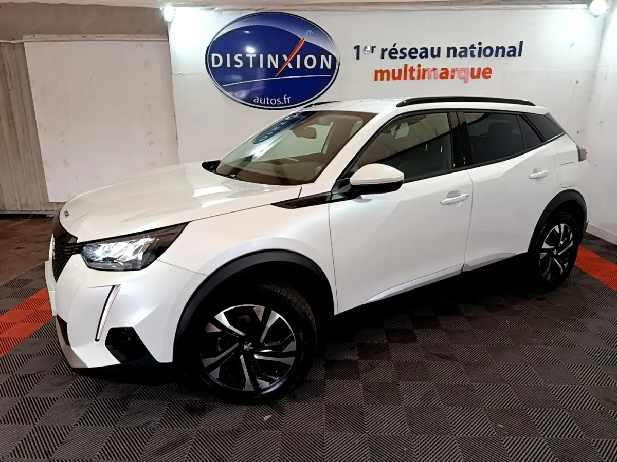 Peugeot 2008 blanc en vue 3/4 avant droit, avec jantes noires et toit noir dans un showroom intérieur.