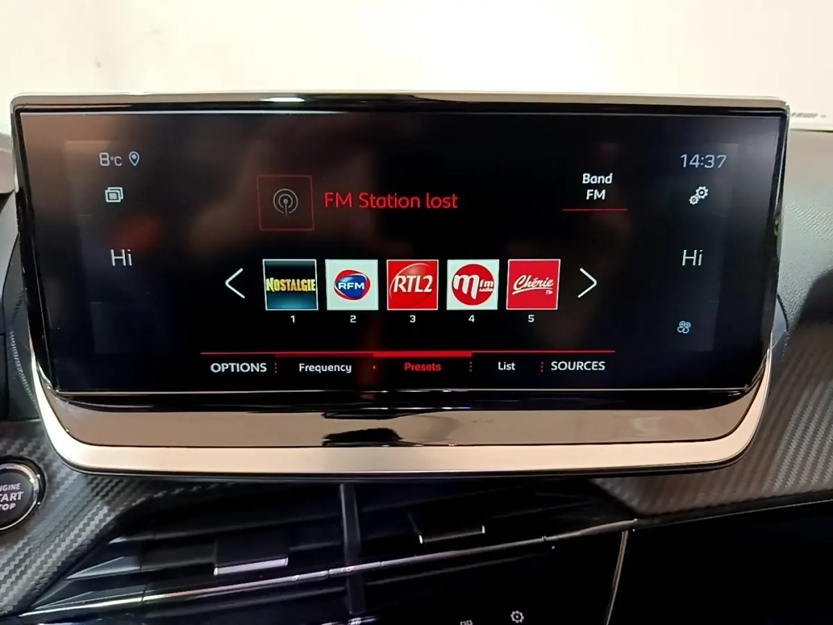 Écran tactile central du tableau de bord du Peugeot 2008 blanc, affichant les stations radio FM.