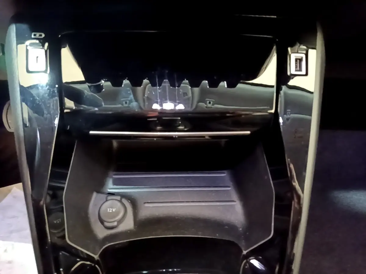 Vue rapprochée de la console centrale noire du Peugeot 2008 blanc, avec prise 12V et ports USB visibles.