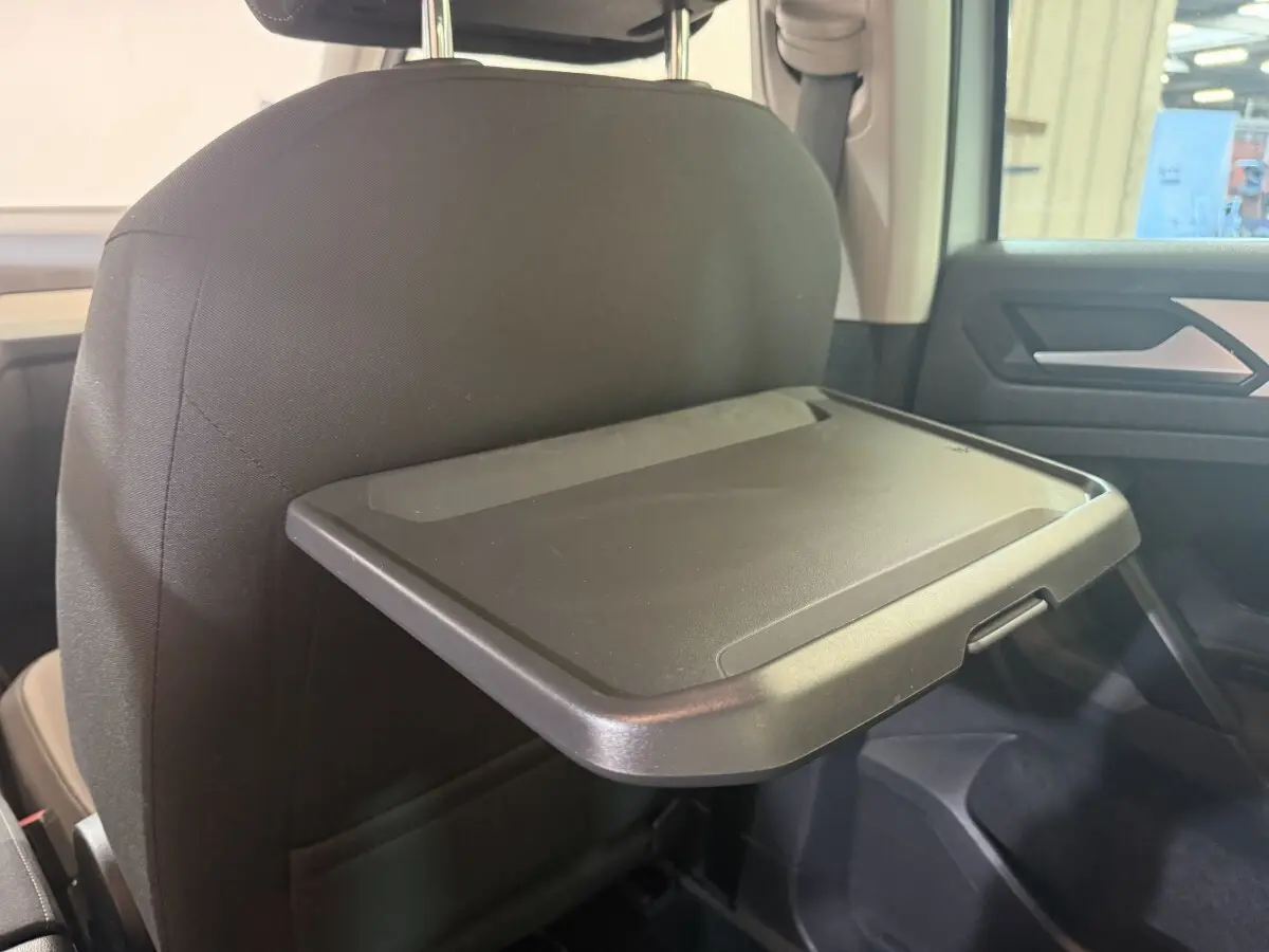 Vue intérieure côté arrière droit du Volkswagen Tiguan 2020, tablette rabattable fixée au dossier du siège avant noir.