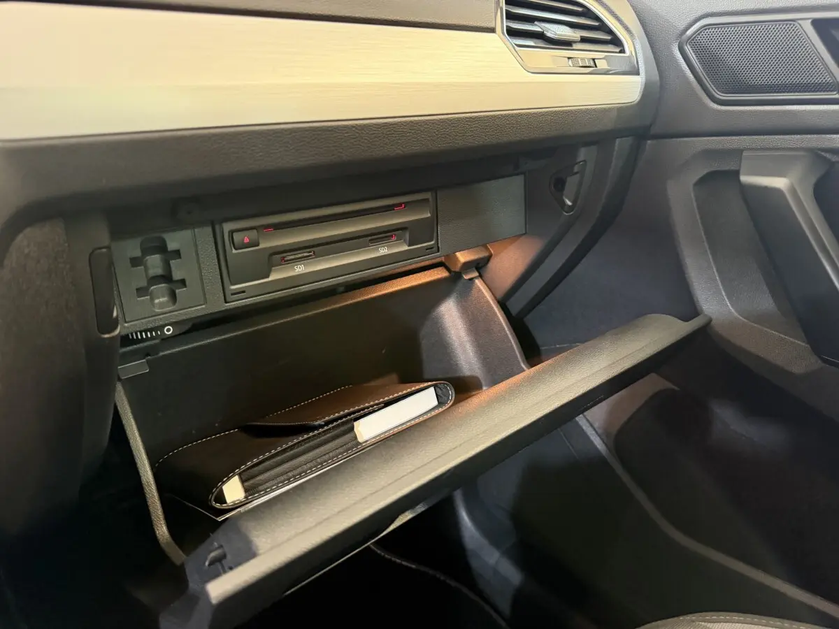 Vue rapprochée de la boîte à gants ouverte côté passager du Volkswagen Tiguan 2020 gris clair, avec manuel de bord visible.
