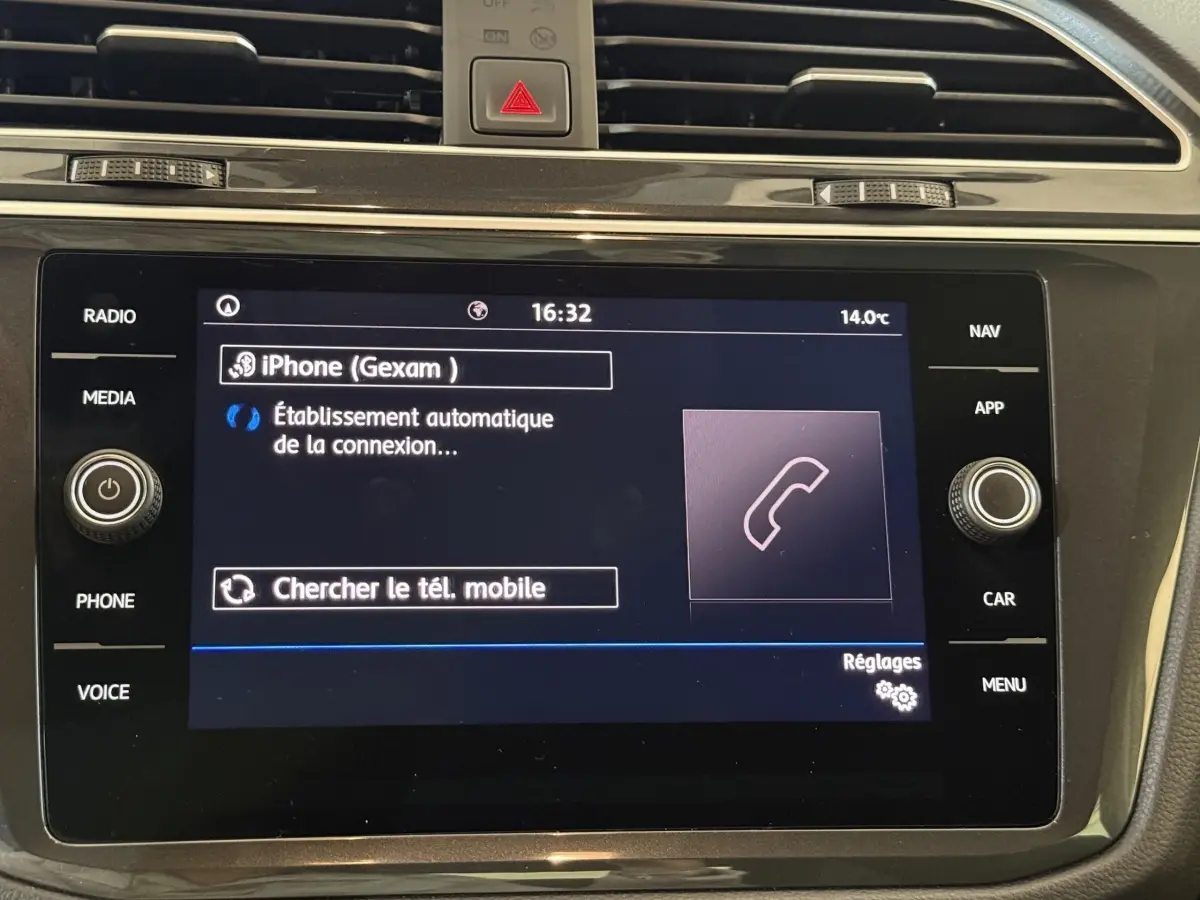Écran tactile central du Volkswagen Tiguan 2020 affichant la connexion Bluetooth d’un iPhone, entouré de commandes noir brillant.