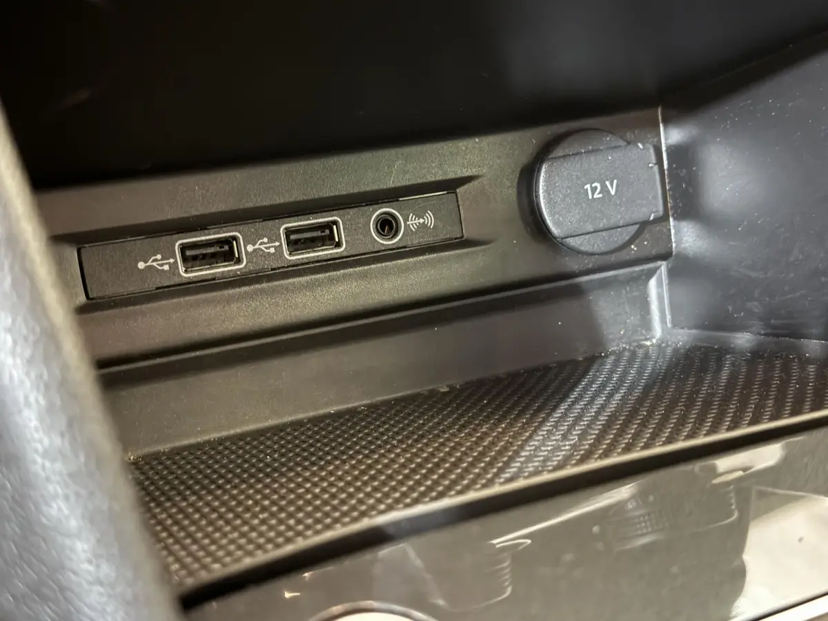 Gros plan sur les ports USB et prise 12V dans l’espace de rangement intérieur du Volkswagen Tiguan gris clair.