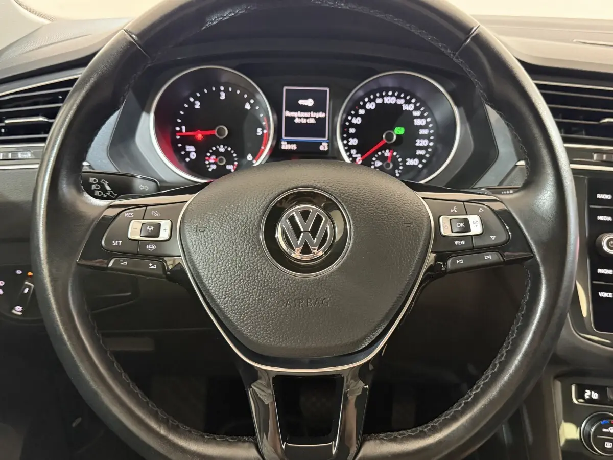 Vue intérieure centrée sur le volant cuir multifonctions noir du Volkswagen Tiguan 2020, avec tableau de bord et écran tactile visibles.