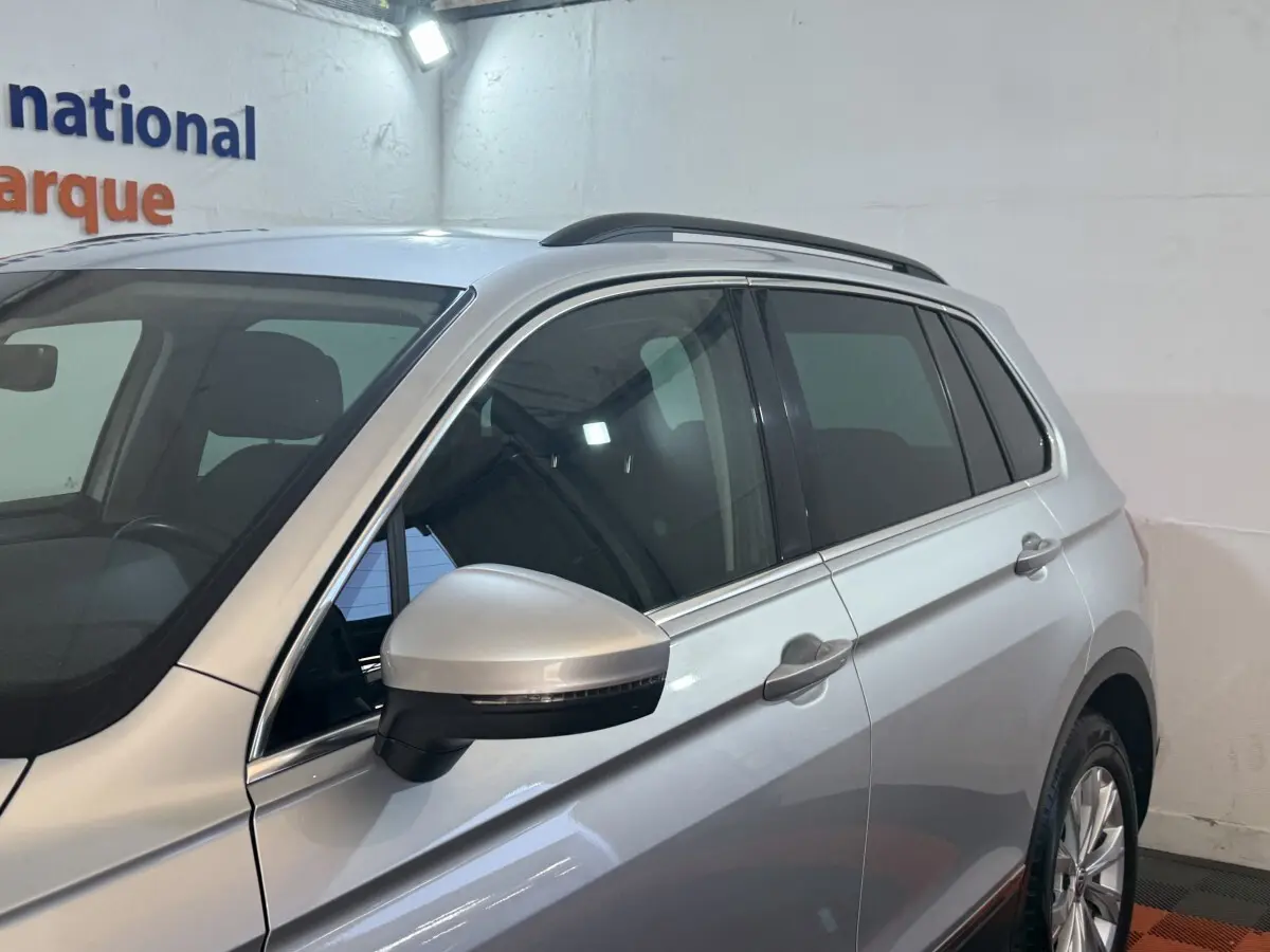 Vue côté gauche avant d'un Volkswagen Tiguan gris clair 2020 avec rétroviseur électrique et vitres teintées.