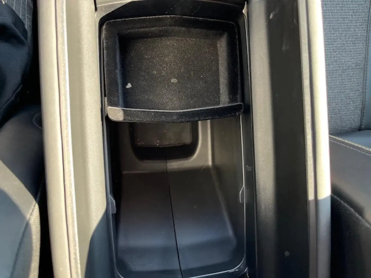 Vue rapprochée de la console centrale noire ouverte du Peugeot 3008, montrant le rangement intérieur entre les sièges.