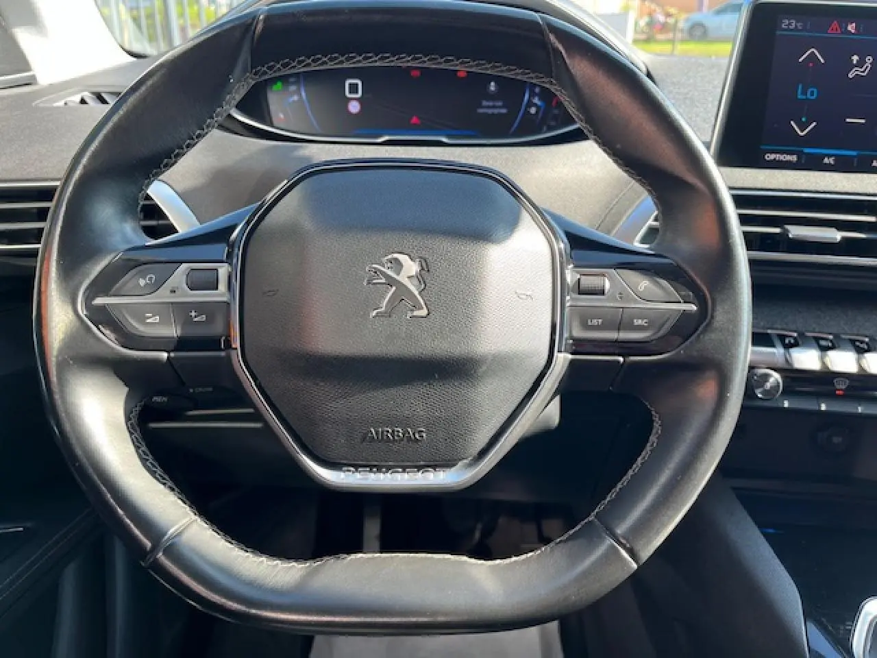 Vue rapprochée du volant noir du Peugeot 3008 2016 avec commandes intégrées et tableau de bord digital en arrière-plan.