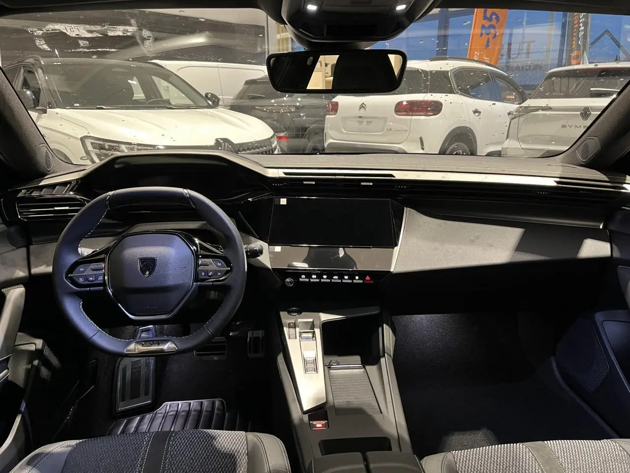 Vue intérieure avant du Peugeot 308 gris Selenium, volant cuir compact et console centrale moderne avec écran tactile noir.