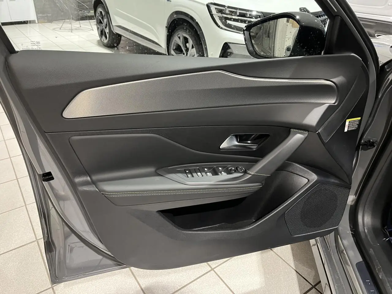 Porte avant gauche ouverte d'une Peugeot 308 GT gris selenium, avec garniture noire et inserts aluminium.
