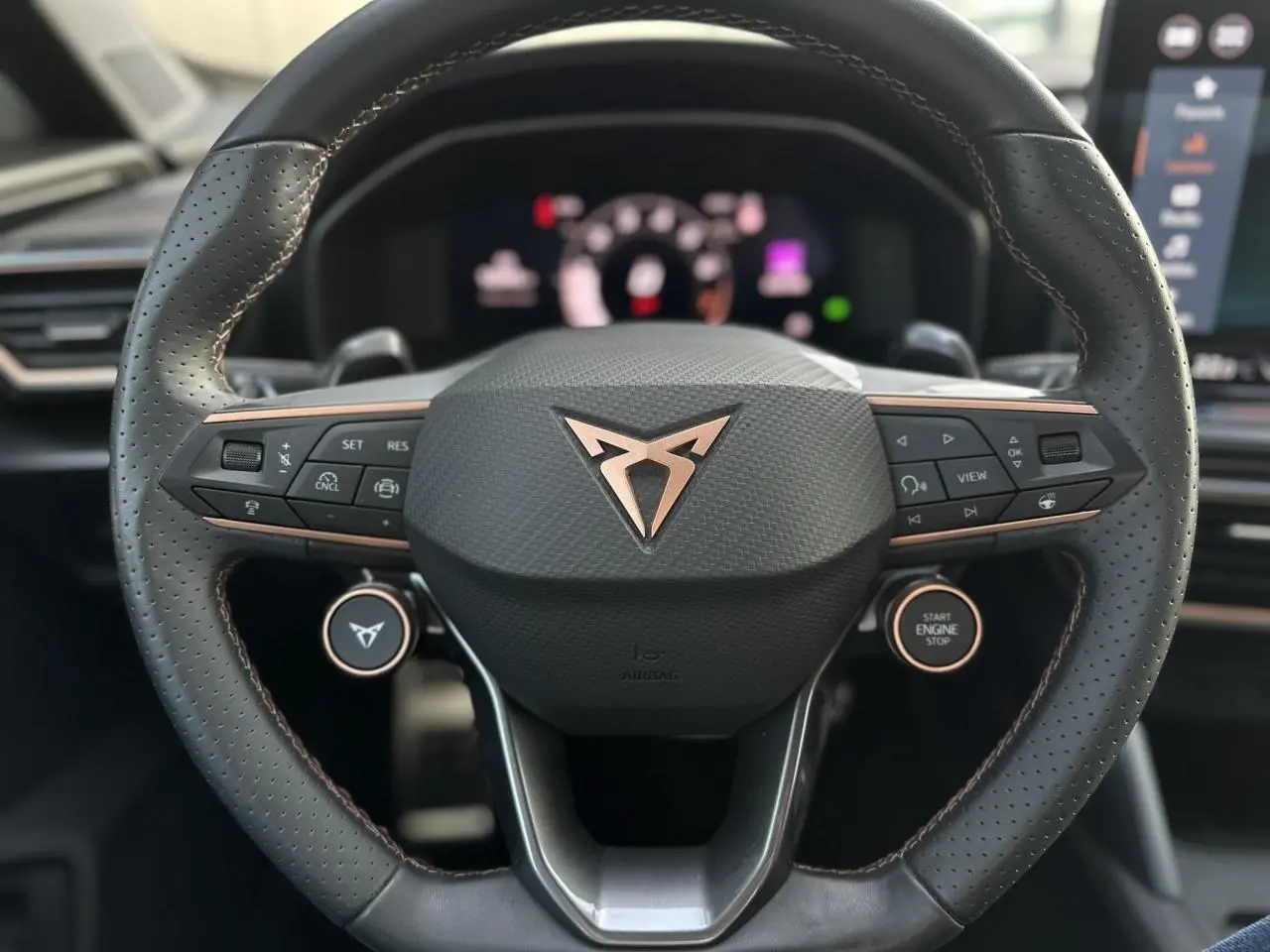 Volant cuir perforé noir avec logo CUPRA cuivré et commandes intégrées, intérieur du Formentor 2025 visible en arrière-plan.