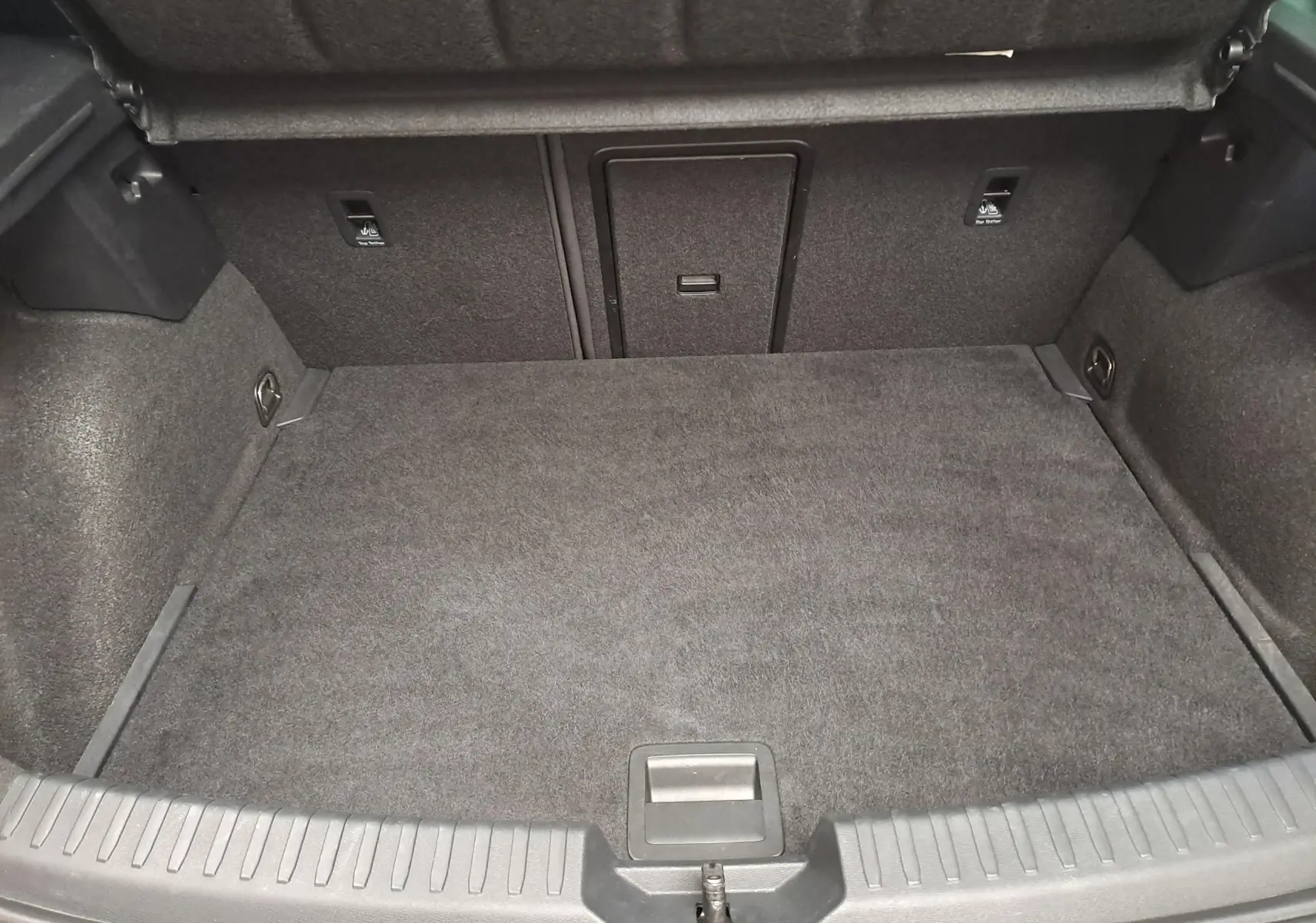 Coffre ouvert de la CUPRA Leon 2023 noir minuit, vue intérieure montrant l'espace de chargement et les fixations.