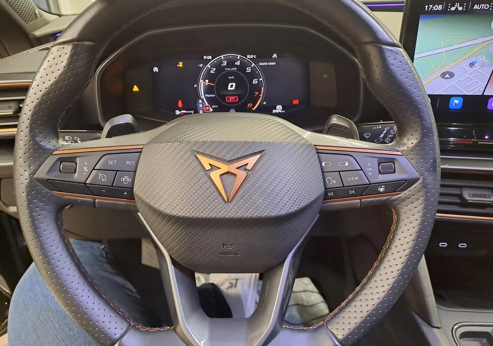 Vue rapprochée du volant en cuir perforé avec logo CUPRA cuivré et tableau de bord numérique du Leon 2023.