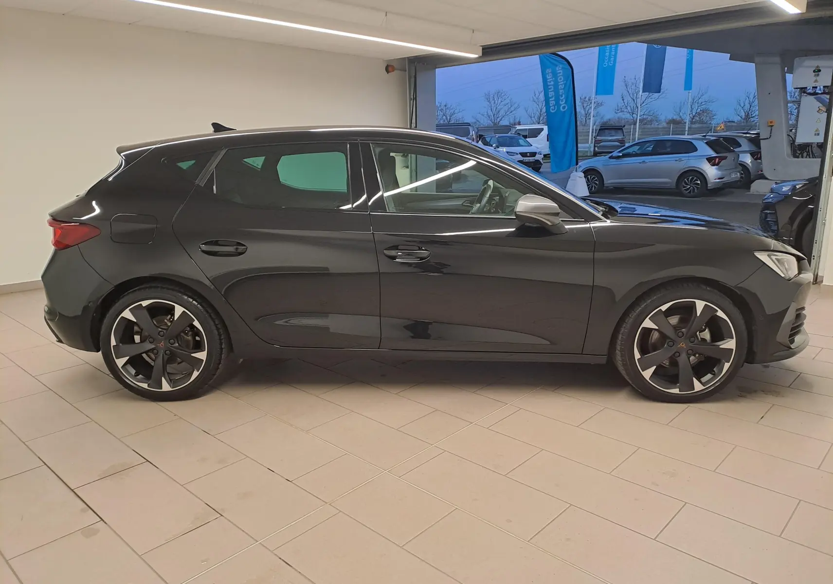 Vue de profil côté droit d'une CUPRA Leon 2023 en peinture métallisée Noir Minuit, avec jantes noires distinctives.