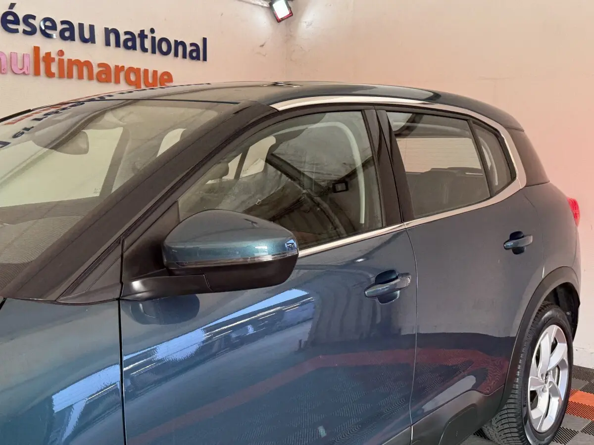 Vue latérale gauche d'un Citroën C5 Aircross bleu métallisé avec rétroviseur électrique et poignées de porte visibles.