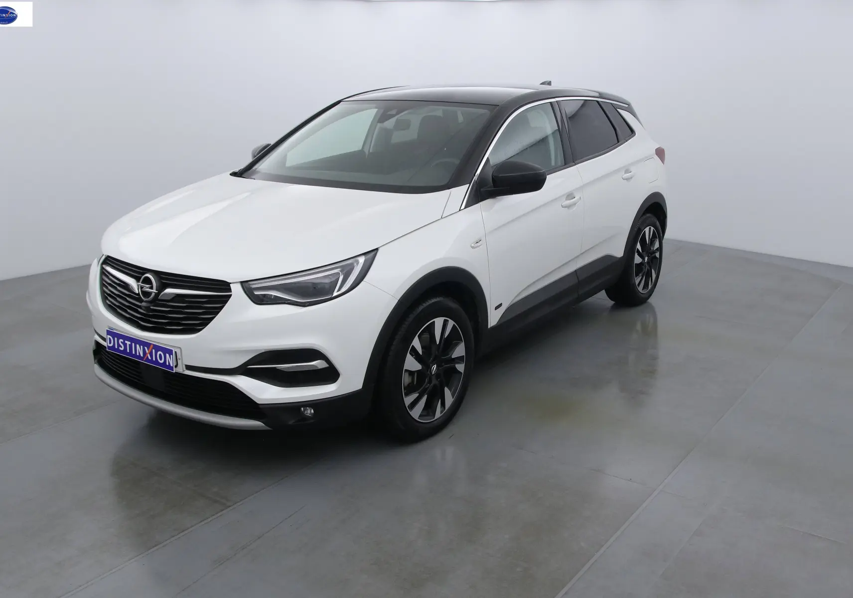 Opel Grandland X blanc métal en vue 3/4 avant droit avec toit noir et jantes bicolores.