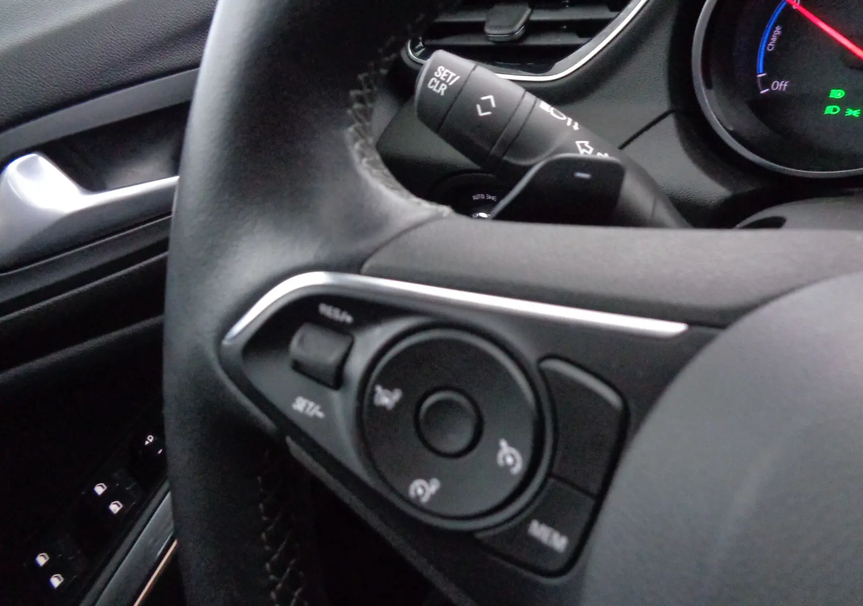 Gros plan sur le volant noir de l'Opel Grandland X 1.6 Hybrid Turbo 2021 avec commandes intégrées et tableau de bord partiel.