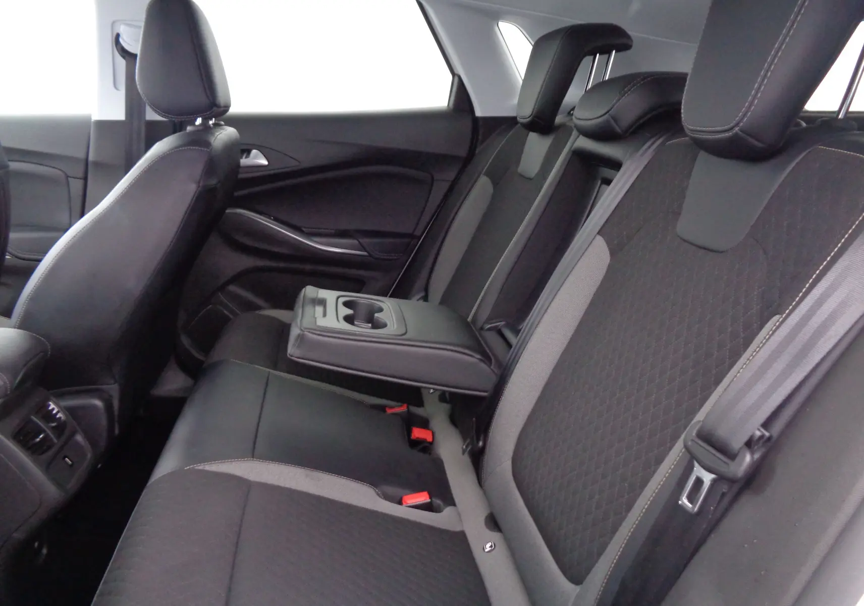 Vue intérieure arrière droite de l’Opel Grandland X 1.6 Hybrid Turbo 2021, sièges noirs avec accoudoir central relevé.