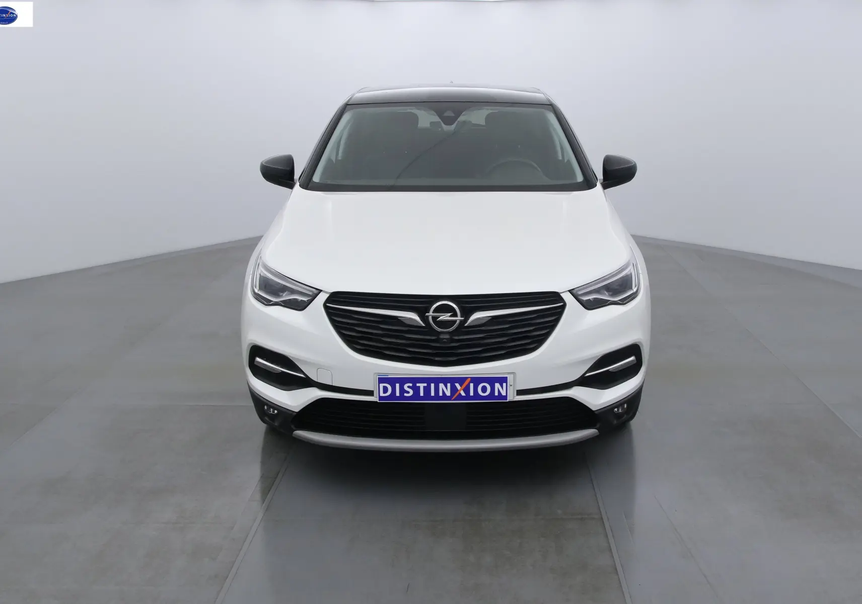 Vue frontale d'un Opel Grandland X blanc métal avec calandre noire et phares LED allumés.