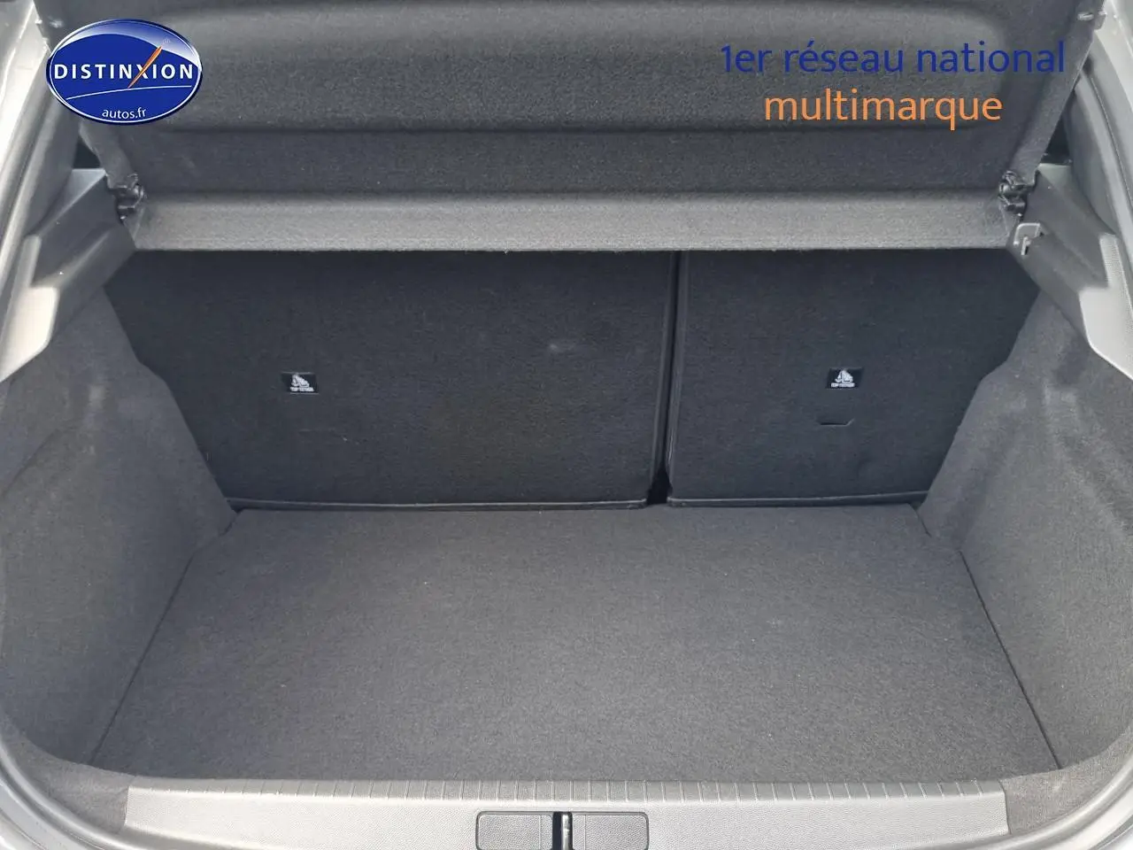 Coffre ouvert vu de face d'une Peugeot 208 gris, montrant l'espace de chargement et la banquette arrière rabattable.