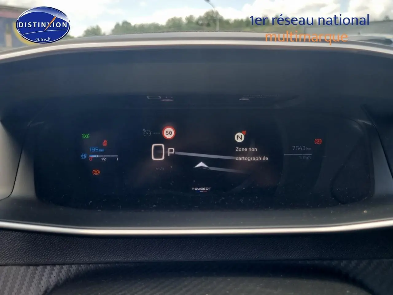 Tableau de bord numérique de Peugeot 208 gris 2025 affichant vitesse, autonomie et navigation en mode parking.