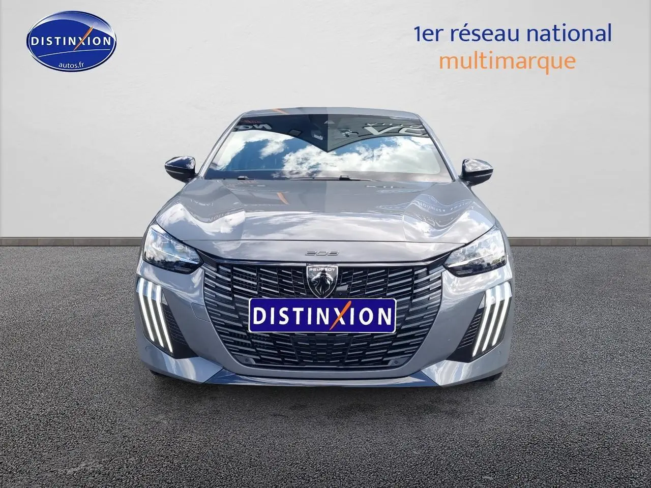 Vue frontale d'une Peugeot 208 gris métallisé avec calandre noire et feux diurnes à LED verticaux allumés.