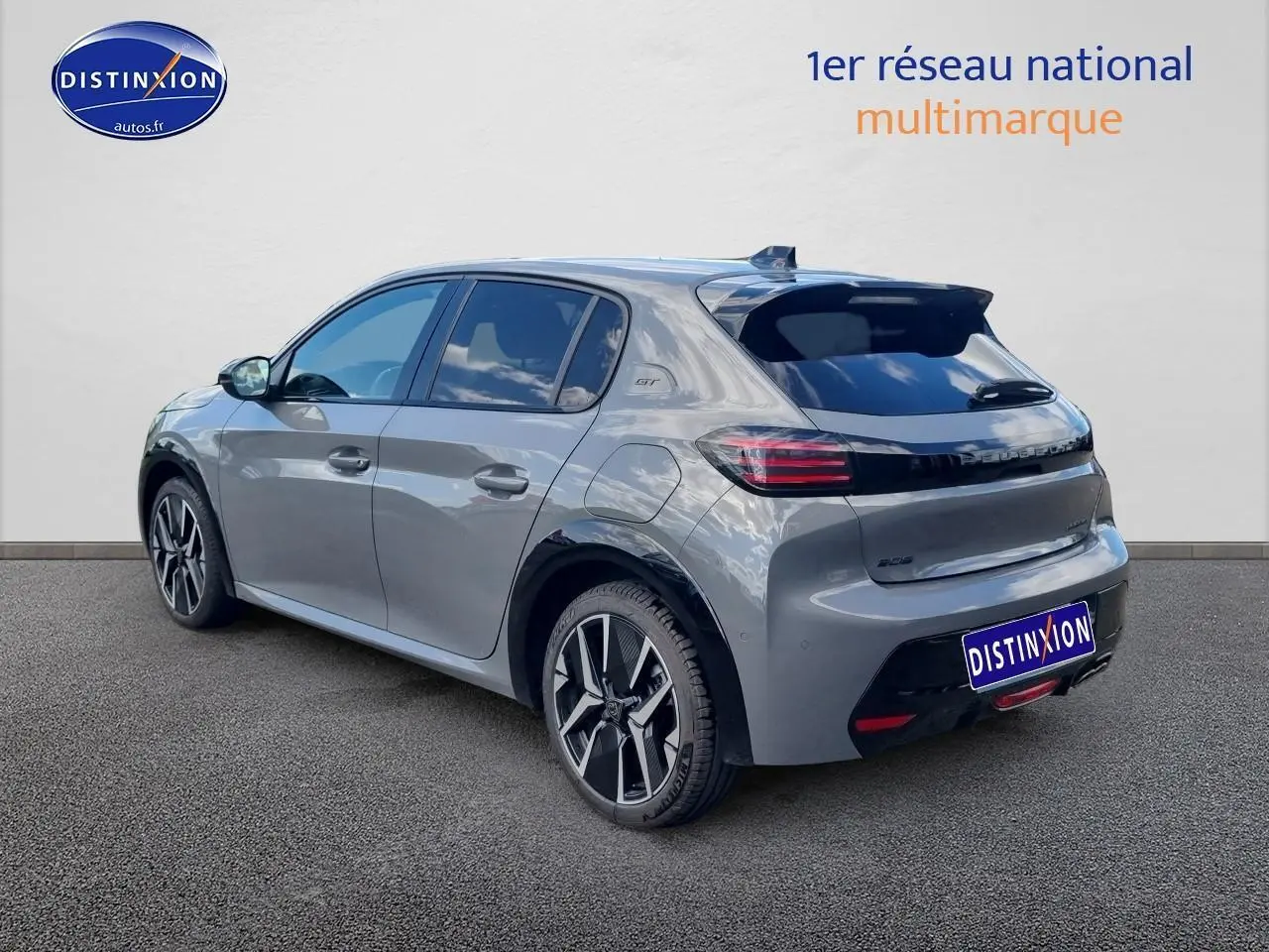 Peugeot 208 gris vue 3/4 arrière droit, jantes alu 17 pouces et toit noir avec badge GT visible.