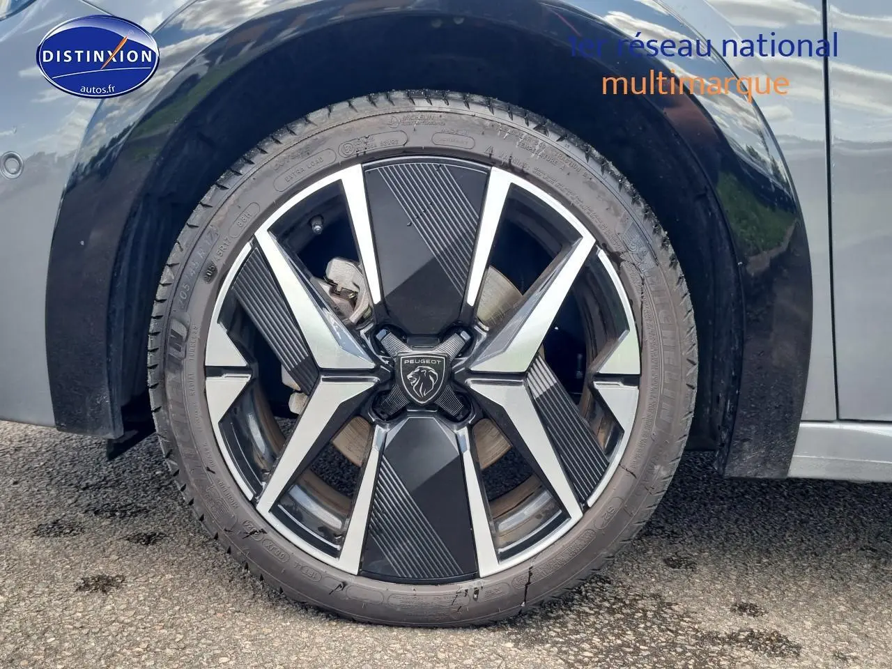 Gros plan sur la jante alu 17 pouces noire et argentée d'une Peugeot 208 gris côté avant droit.