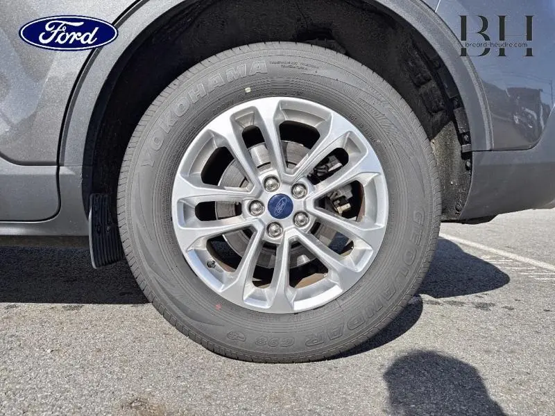 Gros plan sur la roue avant droite en jante alu du Ford Kuga gris métallisé 2022, avec logo Ford central visible.