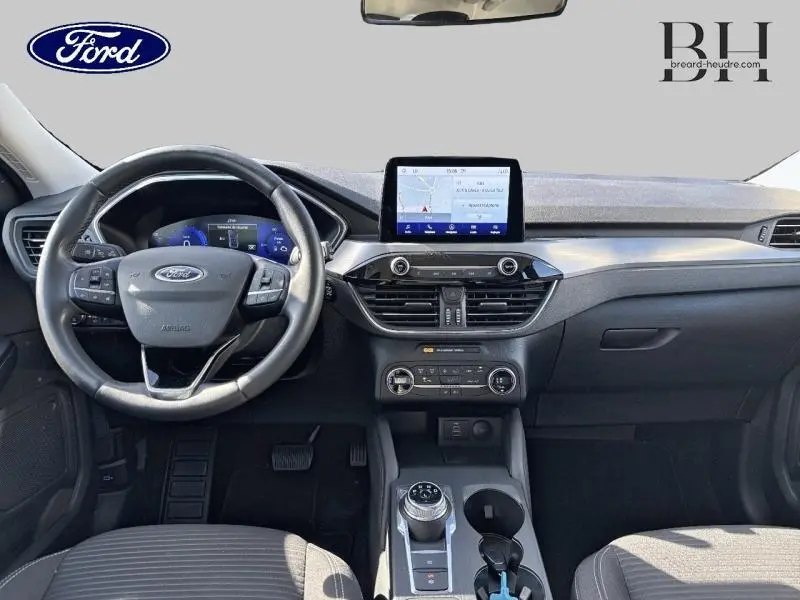 Vue intérieure avant du tableau de bord et volant cuir multifonction du Ford Kuga gris avec écran tactile GPS et console centrale moderne.