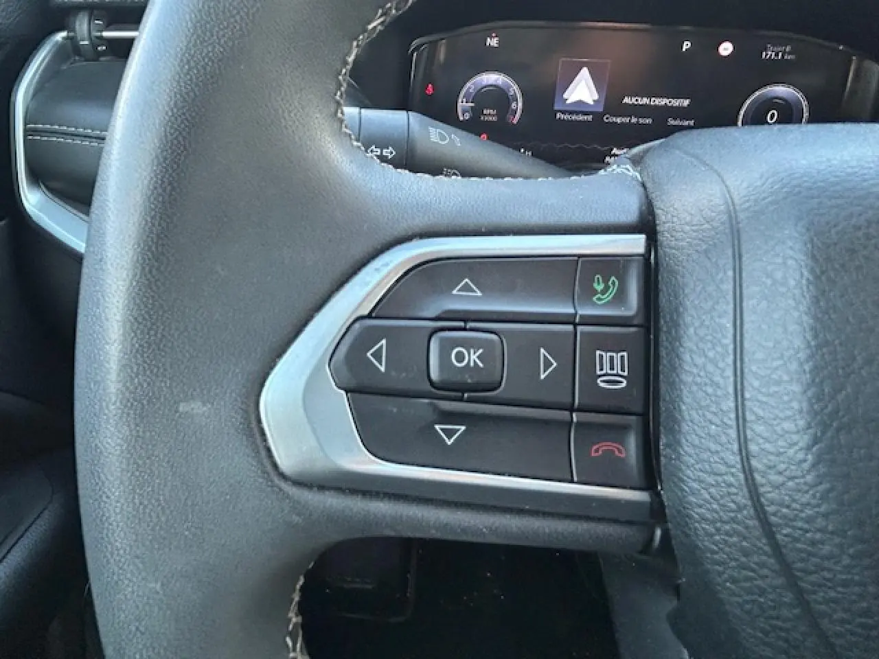 Gros plan sur les commandes gauche du volant noir du Jeep Compass 2021 avec affichage numérique en arrière-plan.