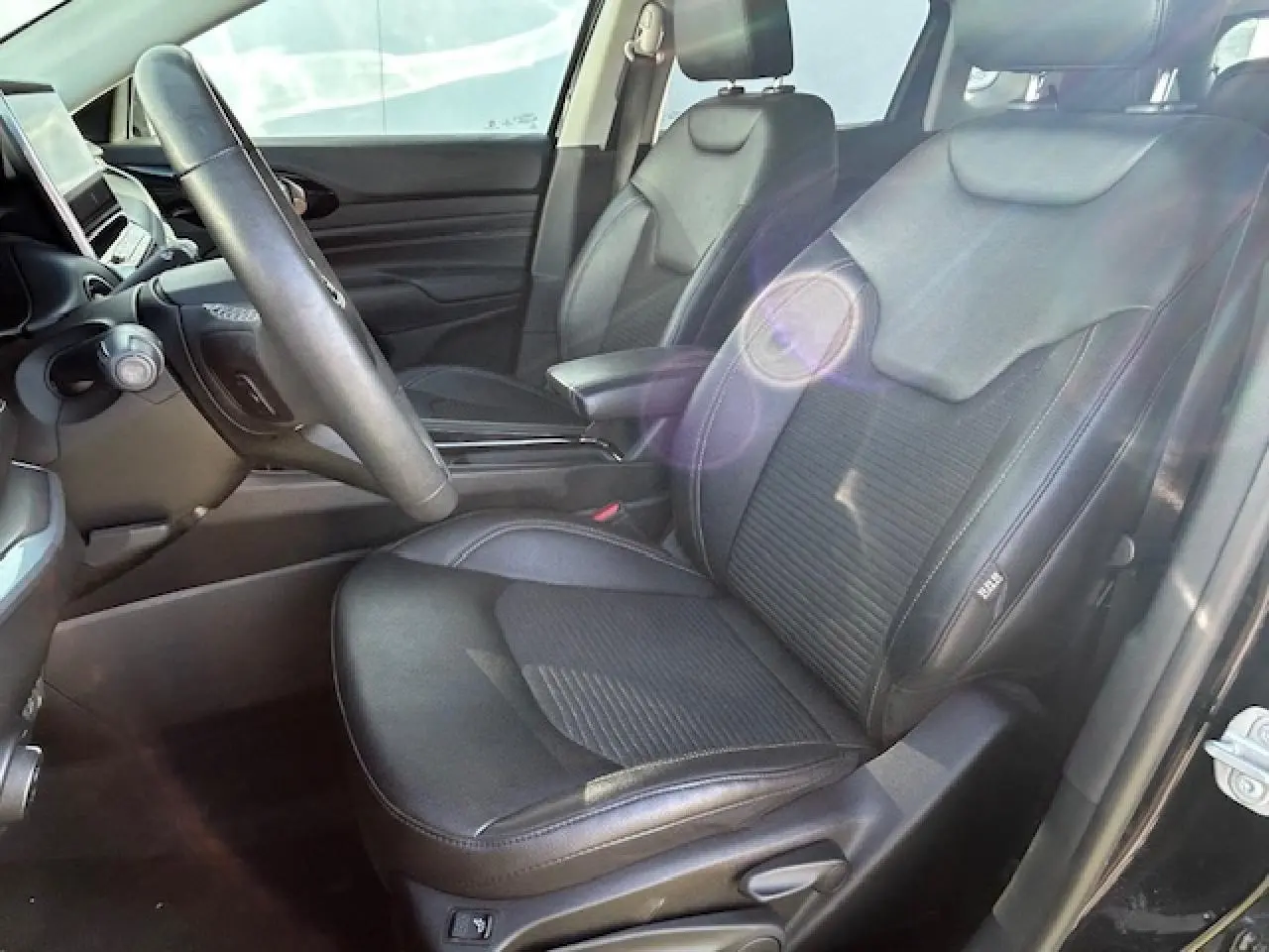 Vue intérieure côté conducteur du Jeep Compass noir 2021, sièges en cuir mixte TEP/tissu avec accoudoir central.