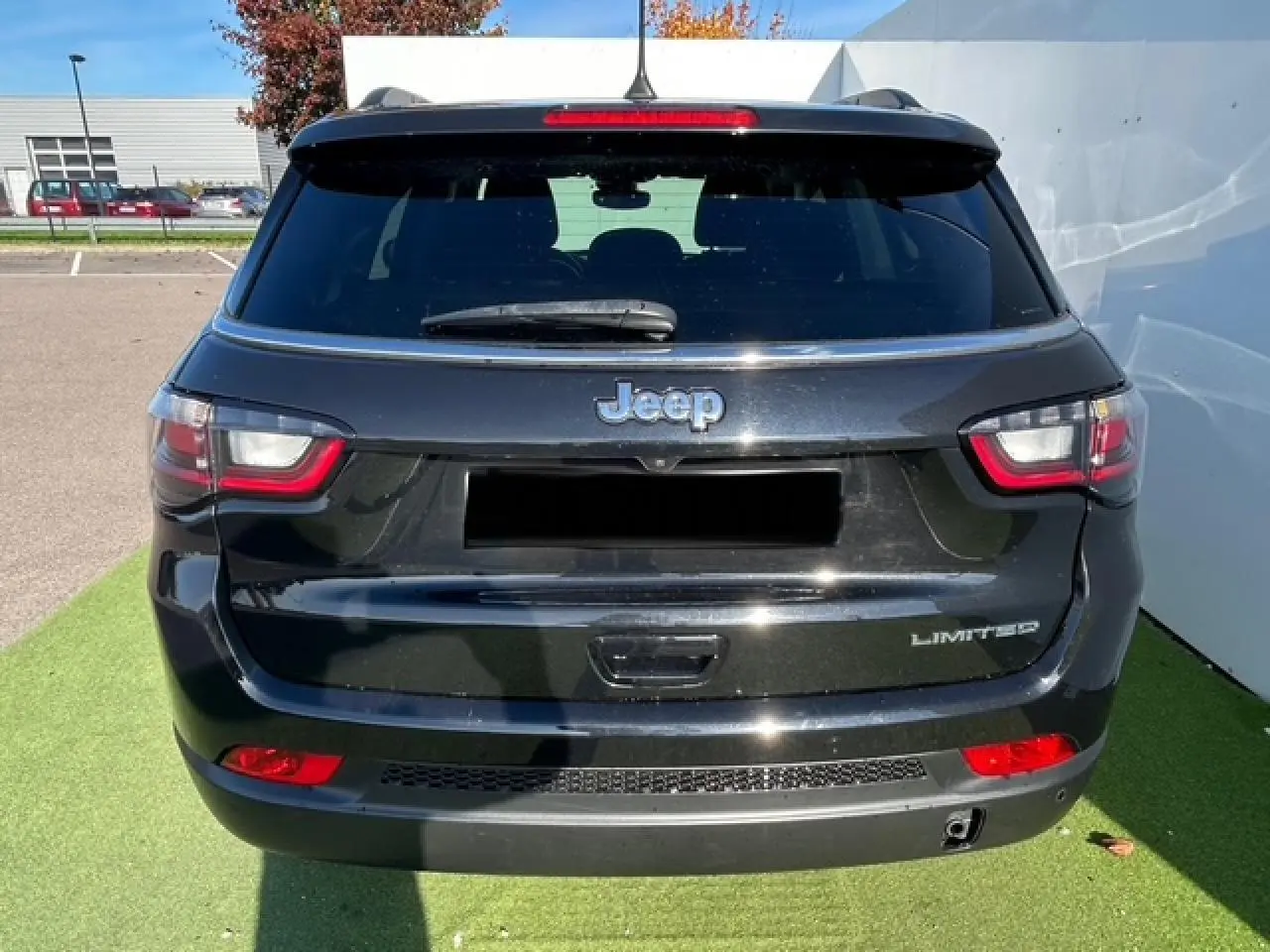 Vue arrière d'un Jeep Compass noir métallisé Limited avec feux LED et logo distinctif sur un parking extérieur.