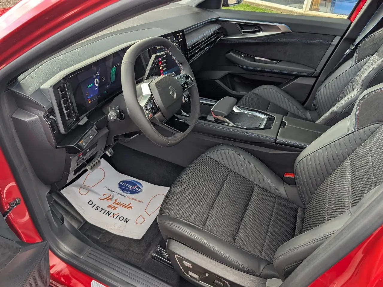 Intérieur avant droit du Renault Austral rouge métallisé, avec sièges en tissu carbone Alcantara et tableau de bord numérique.