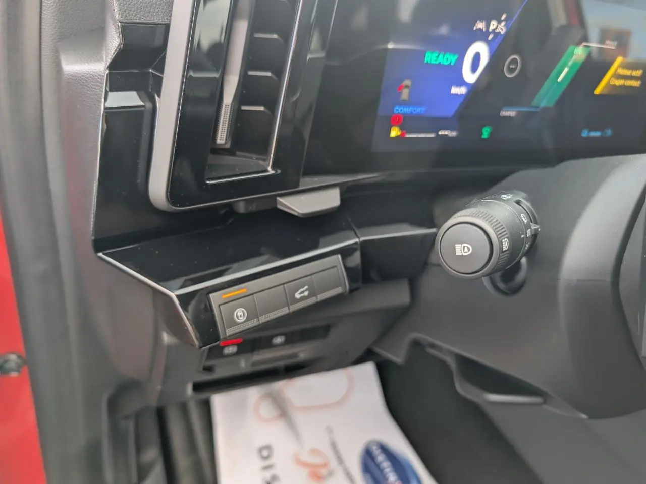 Détail de la planche de bord côté gauche du Renault Austral rouge, avec commandes et écran numérique allumé.