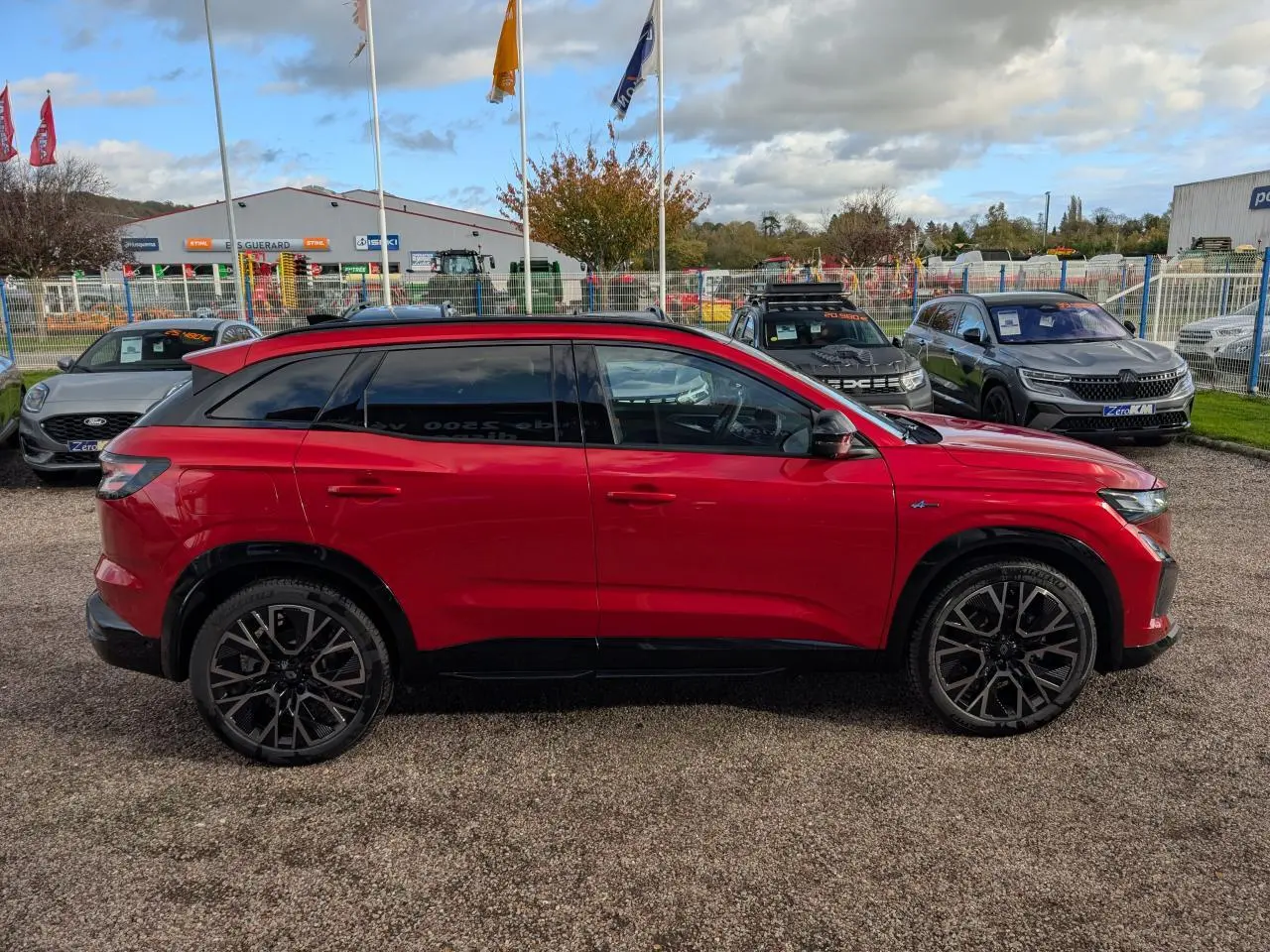 Profil côté gauche du Renault Austral rouge métallisé 2025 avec jantes alliage noires et toit panoramique.