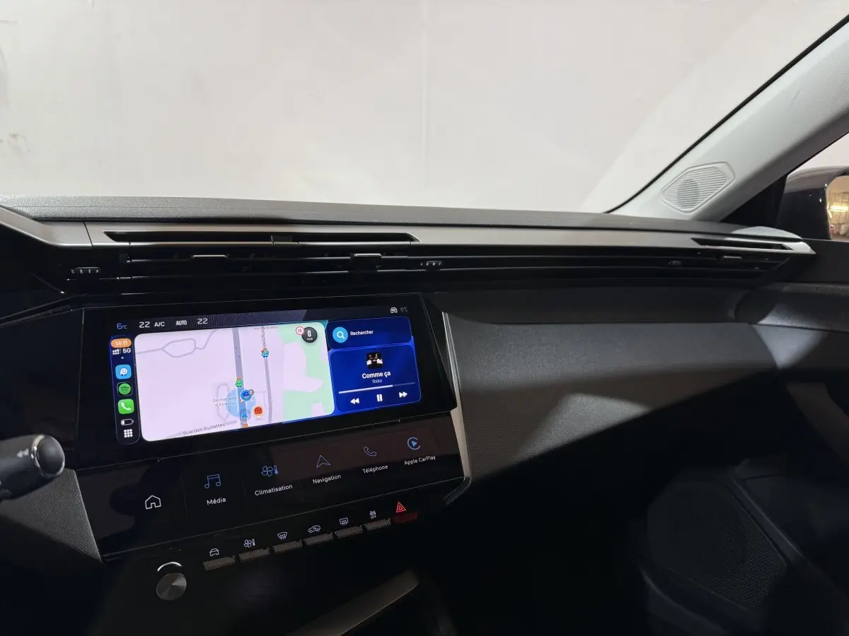 Tableau de bord intérieur de Peugeot 308 rouge 2025, vue côté passager avec écran tactile central allumé.