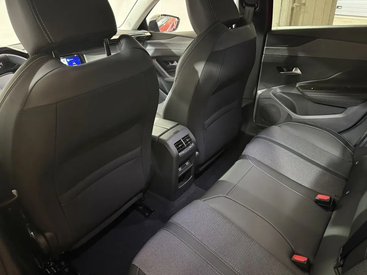 Vue arrière intérieure du Peugeot 308 rouge 2025, sièges arrière en cuir noir avec aérateurs centraux visibles.