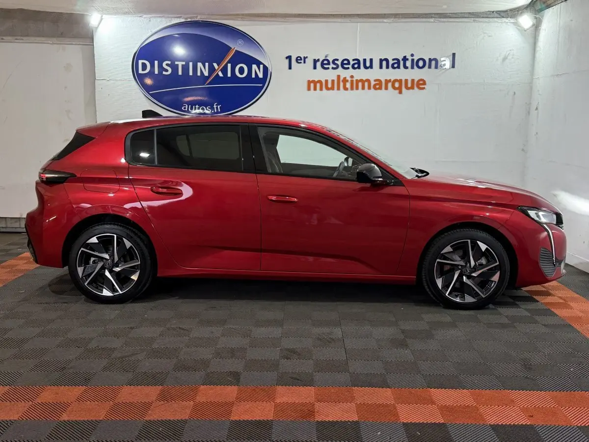 Profil droit de la Peugeot 308 rouge 2025 avec jantes alliage et lignes dynamiques en arrière-plan showroom.
