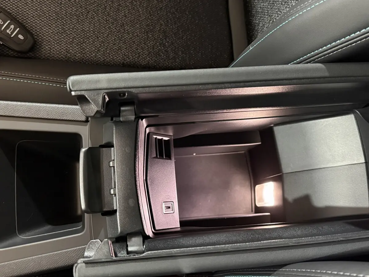 Vue plongeante sur le rangement central ouvert de la Peugeot 308 rouge, intérieur noir avec éclairage LED intégré.