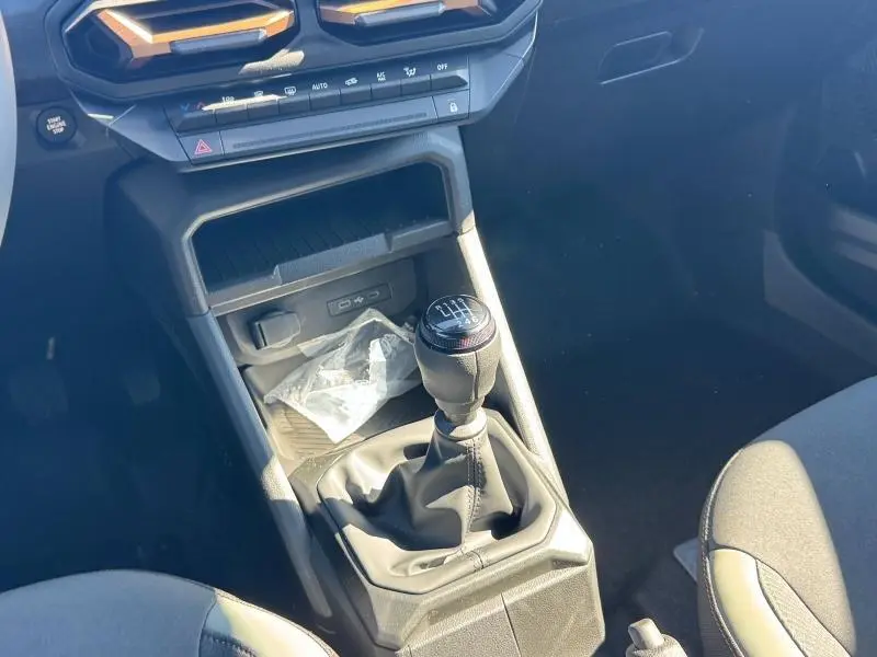 Vue rapprochée de la console centrale du Dacia Duster blanc 2025 avec levier de vitesse manuel et commandes climatisation.