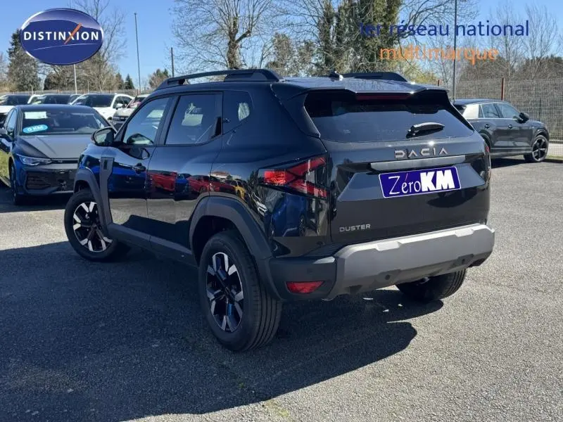 Vue 3/4 arrière droite d'un Dacia Duster noir avec barres de toit et jantes alliage sur parking.