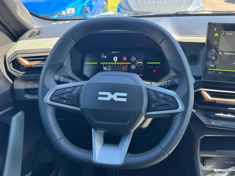 Vue frontale du volant noir du Dacia Duster 2025 avec tableau de bord numérique et écran tactile latéral.